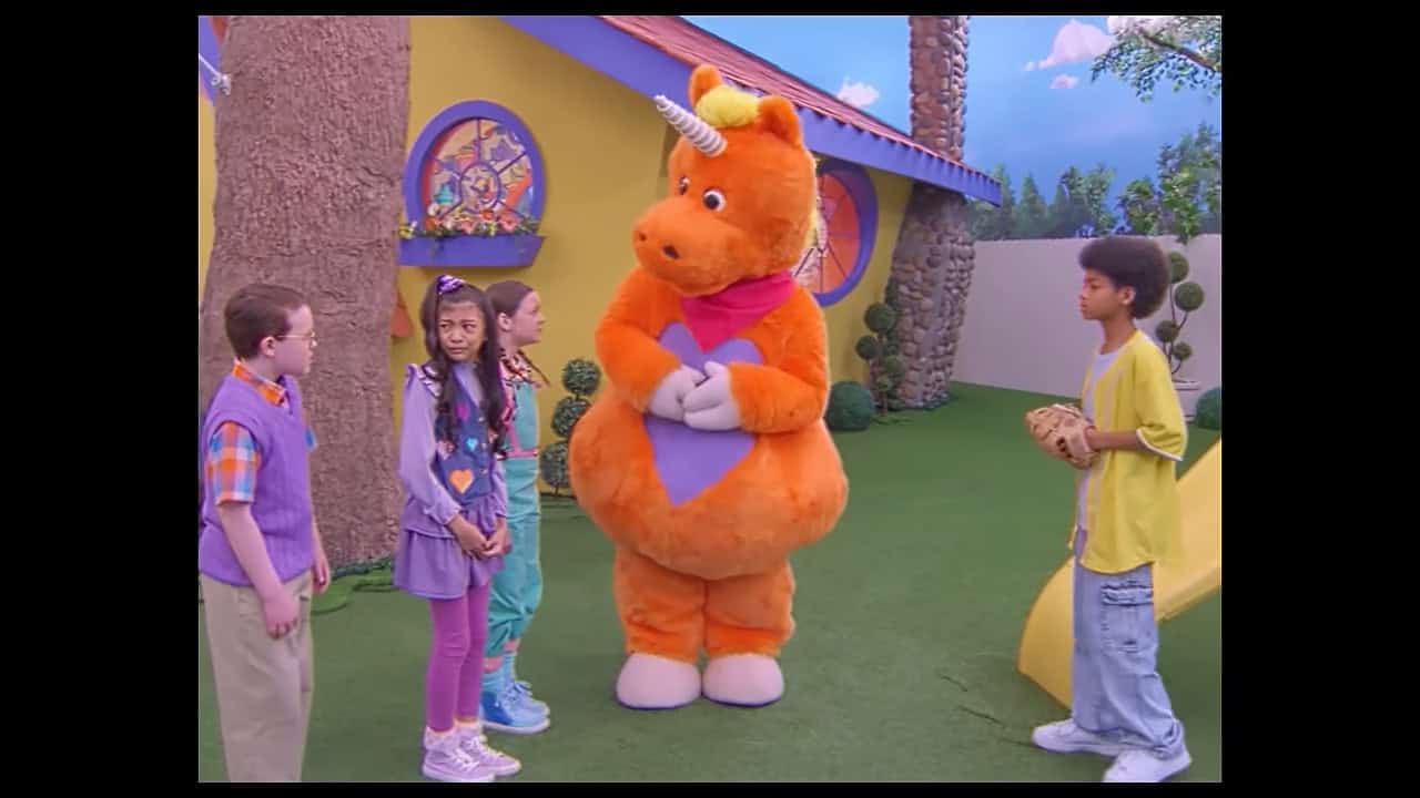 On the It's Buddy set outside the birghtly colored clubhouse in an AstroTurf yard, one kid stands with a baseball and mitt looking happy and three other kids stand to the other side looking upset. Buddy stands between them, looking at the upset kids expectantly with his hands folded.